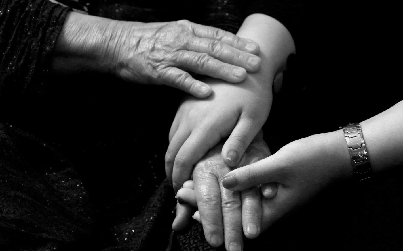 a black and white photo of two people holding hands by razi pouri courtesy of Unsplash.