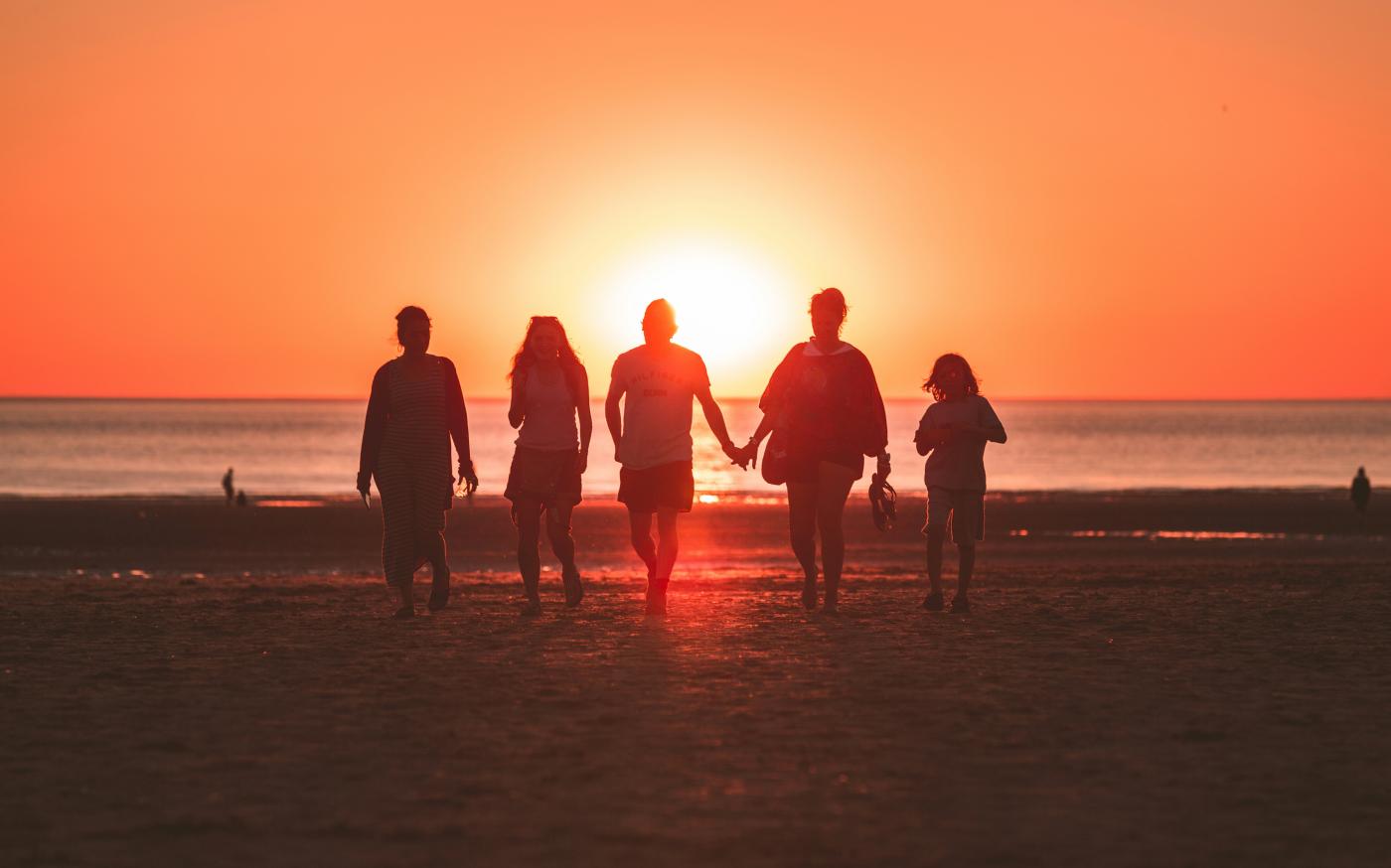 silhouette photo of five person walking on seashore during golden hour by Kevin Delvecchio courtesy of Unsplash.
