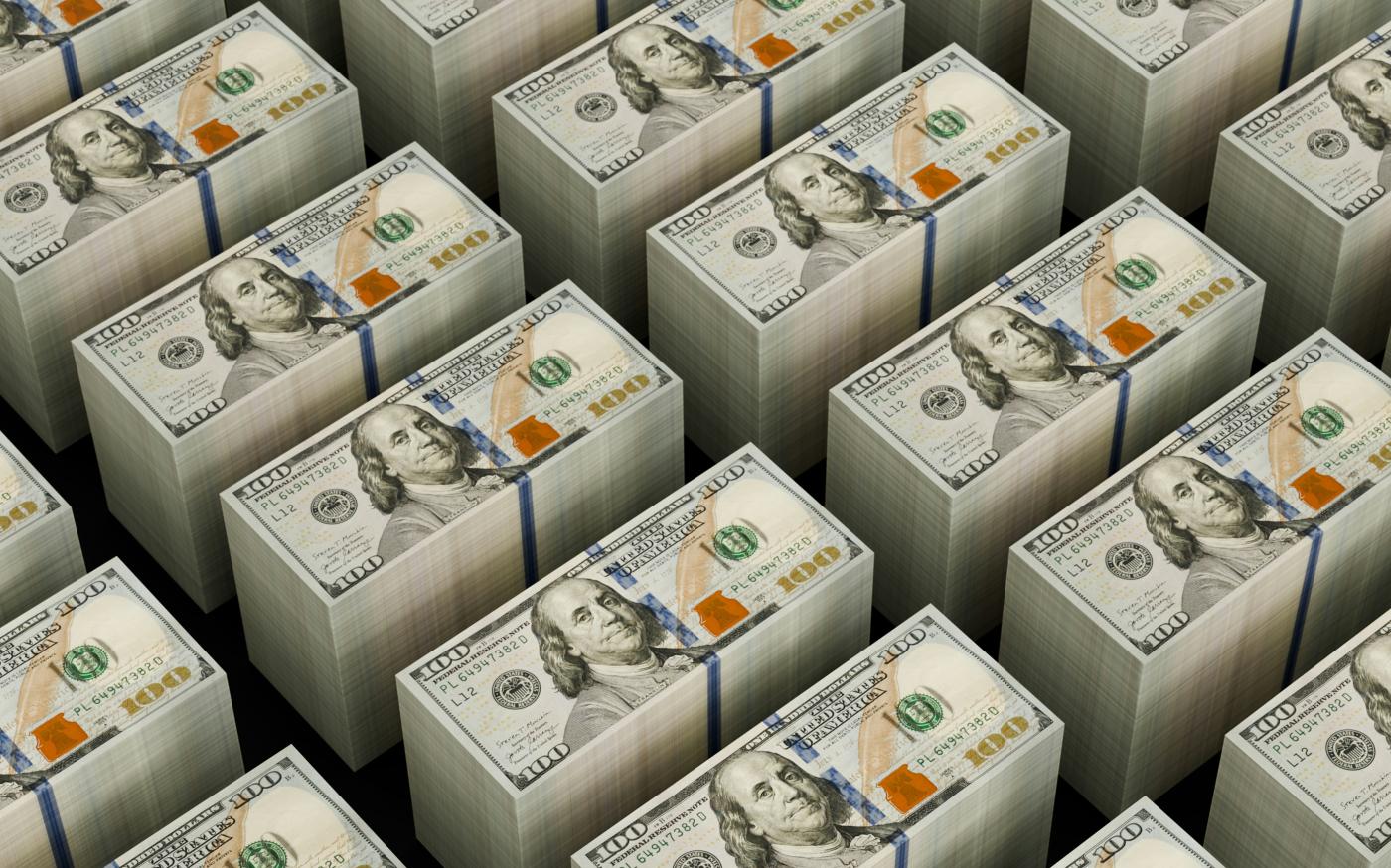 Stacks of hundred dollar bills are shown. by Logan Voss courtesy of Unsplash.