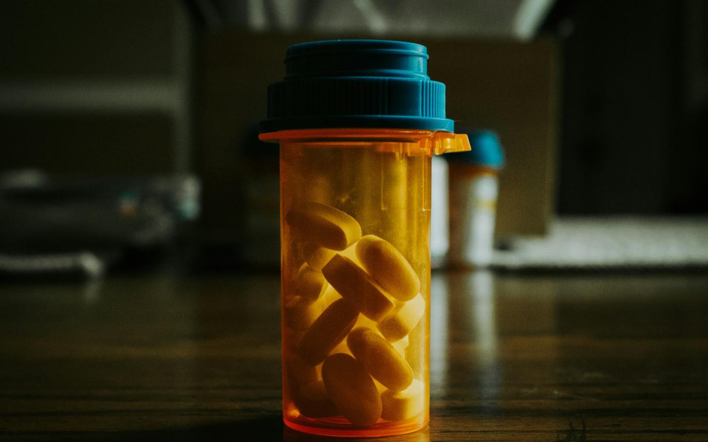 a bottle filled with pills sitting on top of a wooden table by Bruno Guerrero courtesy of Unsplash.