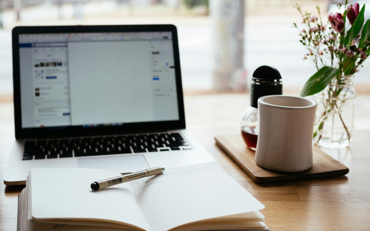 MacBook Pro near white open book by Nick Morrison courtesy of Unsplash.