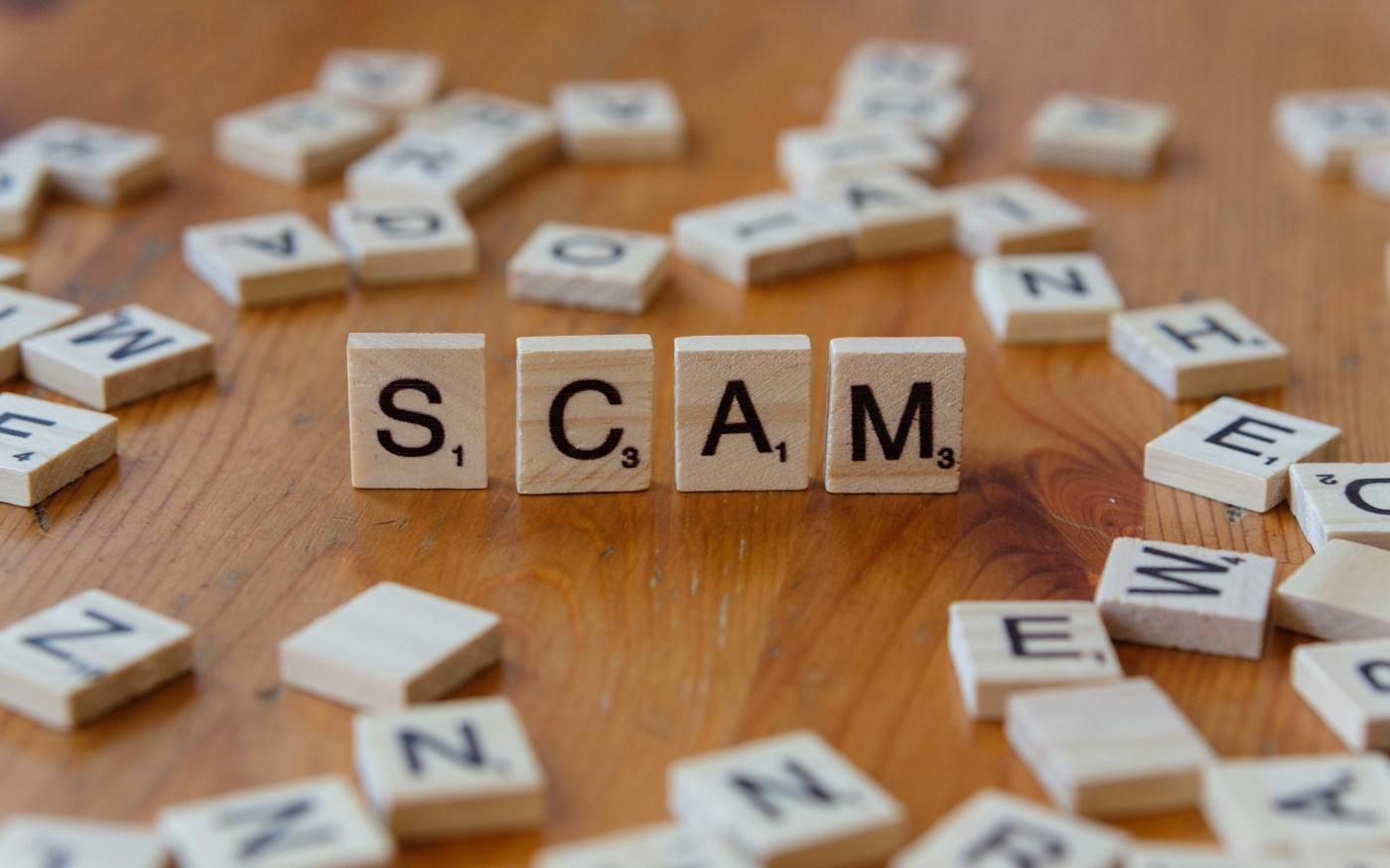 Scam spelled with scrabbles on a wooden table by Markus Winkler courtesy of Unsplash.