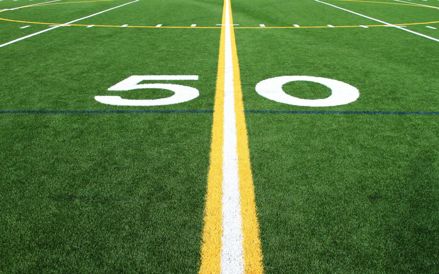 a football field with the number sixty on it by Mario Verduzco courtesy of Unsplash.