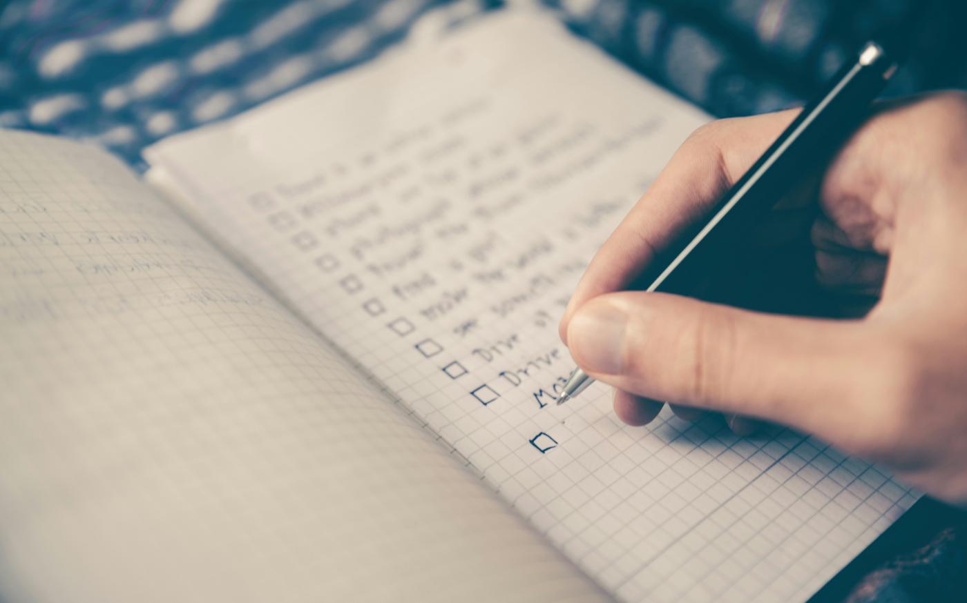 person writing bucket list on book by Glenn Carstens-Peters courtesy of Unsplash.