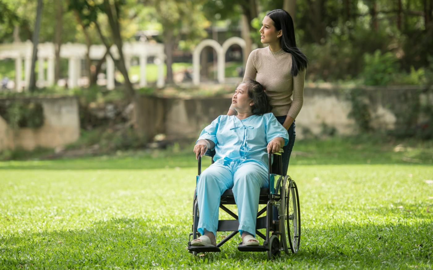 A woman in a wheelchair standing next to a man in a park by Raj Tuladhar courtesy of Unsplash.