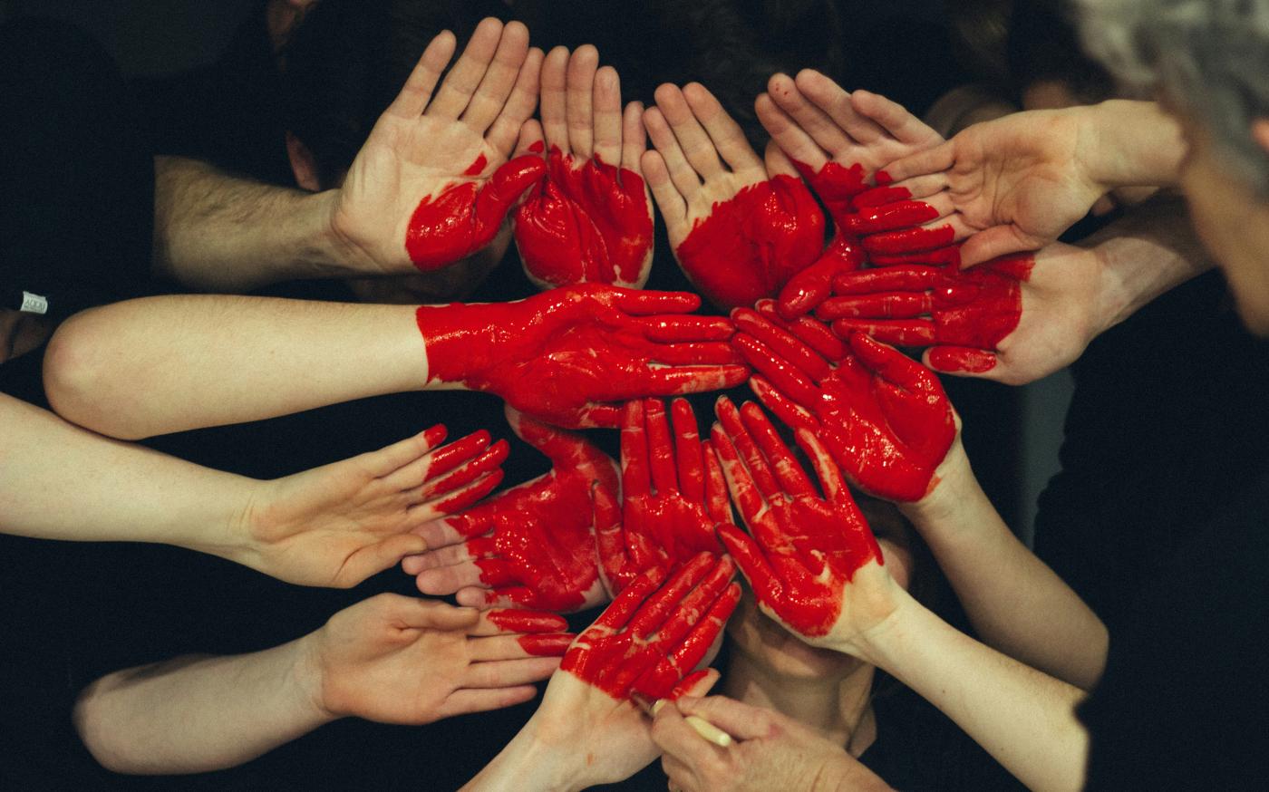 hands formed together with red heart paint by Tim Marshall courtesy of Unsplash.