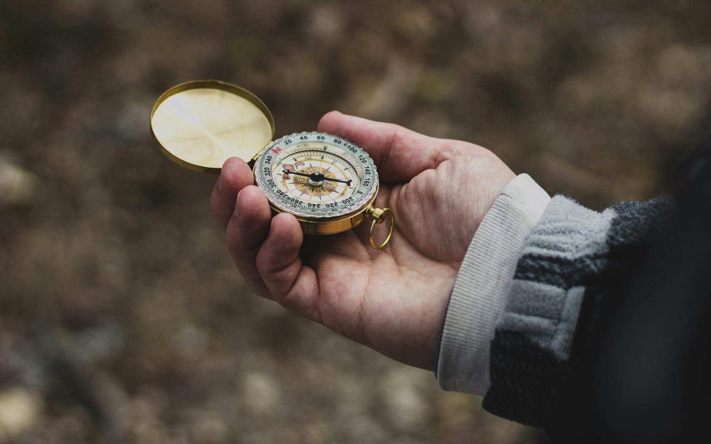 person using white and gold compass by Ethan Sykes courtesy of Unsplash.