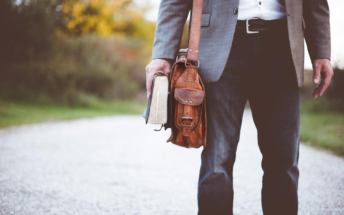 man holding book on road during daytime by Ben White courtesy of Unsplash.