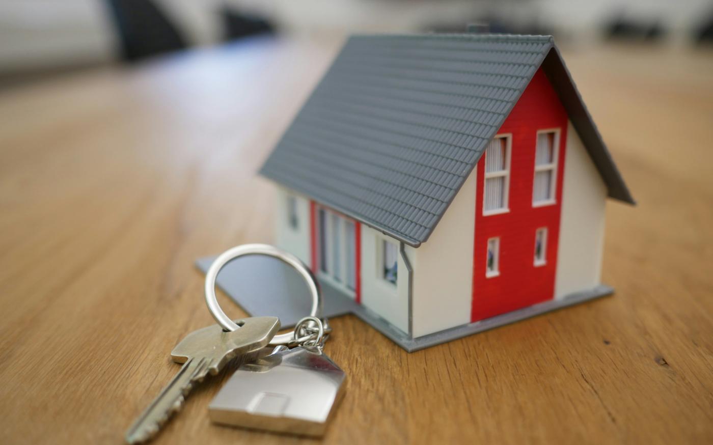 white and red wooden house miniature on brown table by Tierra Mallorca courtesy of Unsplash.