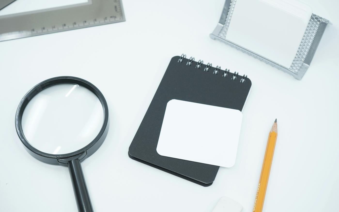 black magnifying glass on white paper by Mediamodifier courtesy of Unsplash.