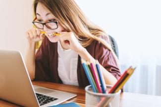 woman biting pencil while sitting on chair in front of computer during daytime by JESHOOTS.COM courtesy of Unsplash.