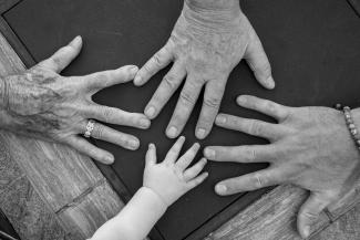 Four hands of different ages reaching towards center by Barnabas Piper courtesy of Unsplash.