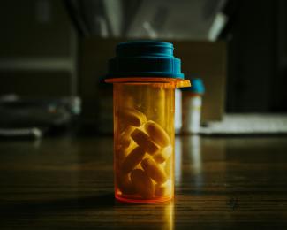 a bottle filled with pills sitting on top of a wooden table by Bruno Guerrero courtesy of Unsplash.