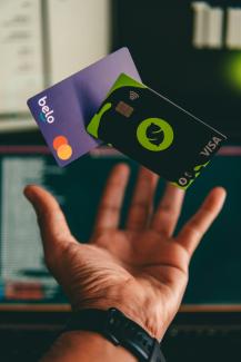 a hand holding a credit card in front of a computer by Diego Gennaro courtesy of Unsplash.