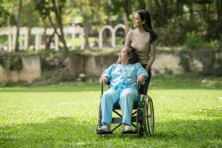 A woman in a wheelchair standing next to a man in a park by Raj Tuladhar courtesy of Unsplash.
