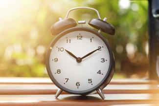 an alarm clock sitting on top of a wooden table by Indra Projects courtesy of Unsplash.