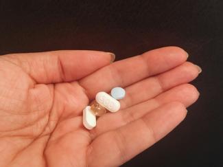 person holding four assorted medicine tablets by pina messina courtesy of Unsplash.